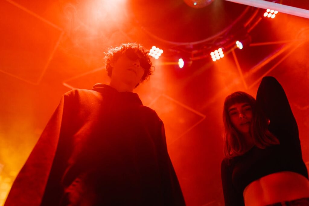 Two young adults enjoying an energetic night at a club under dynamic red lighting.